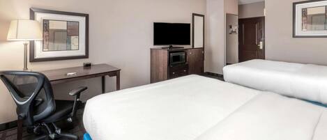 A hotel room with a bed, a desk with a chair, a TV, and a microwave.