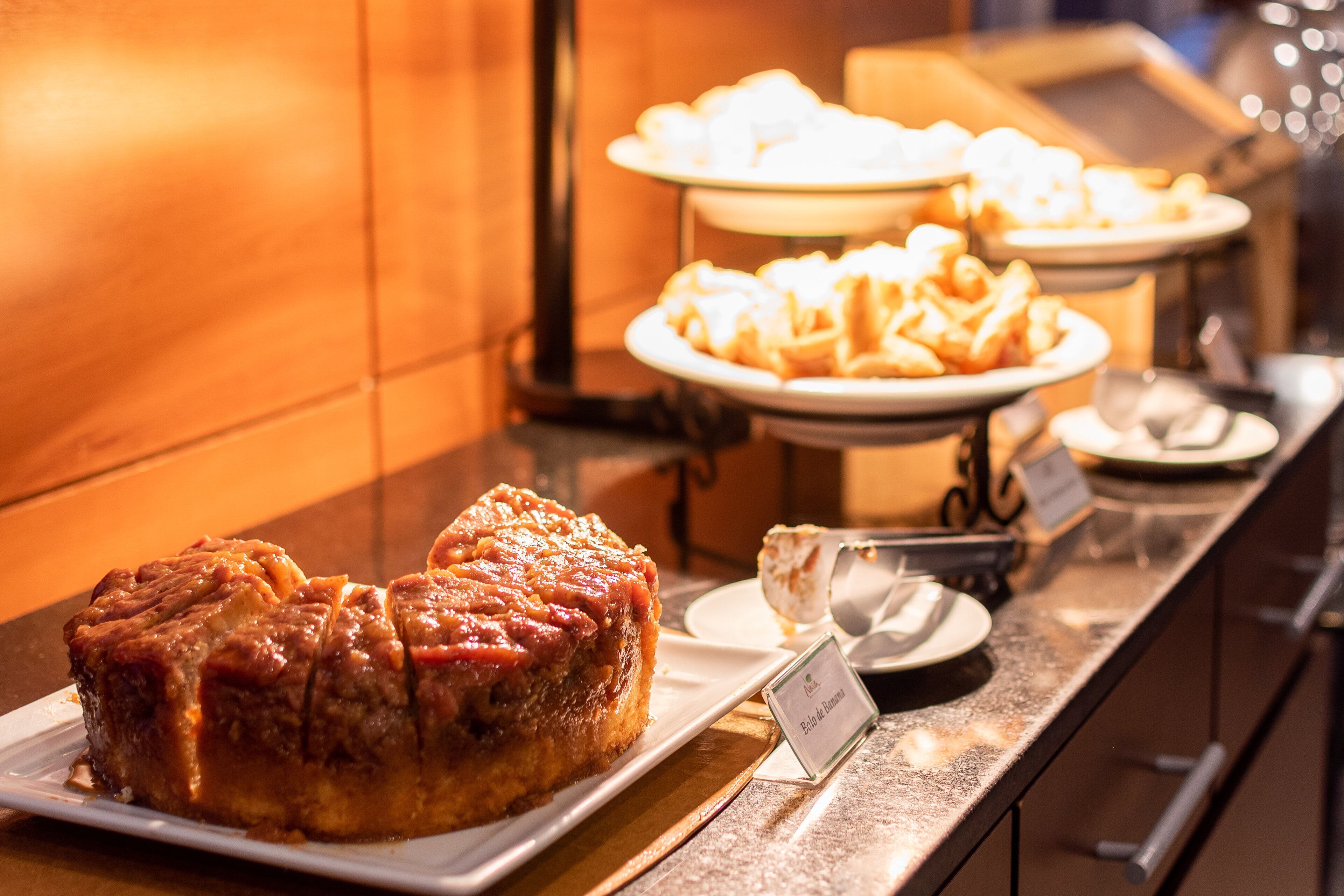 A buffet with various desserts, including a large piece of cake and several plates of pastries.
