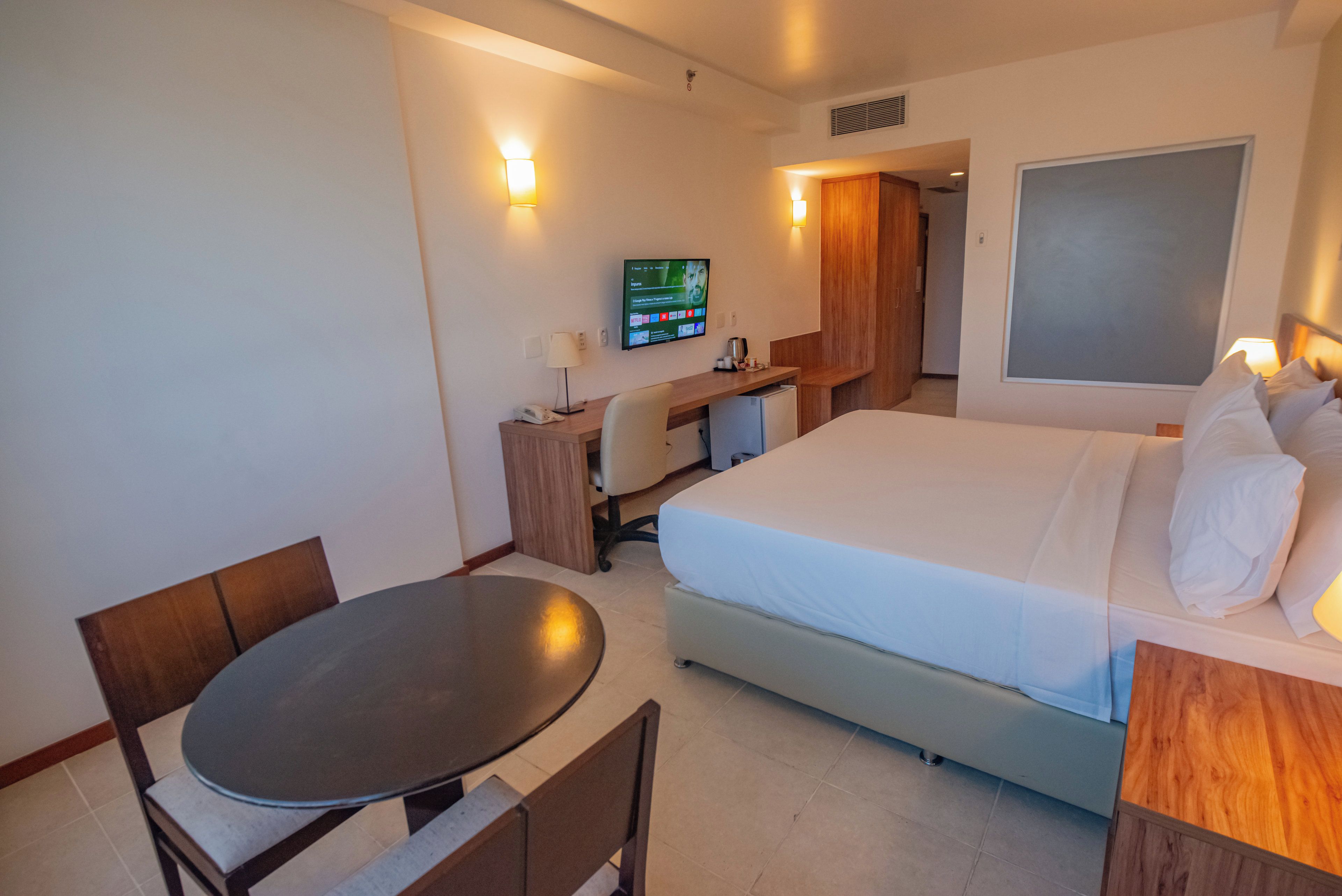 Una camera d'albergo con un letto, una scrivania, una sedia, un tavolo e un televisore.