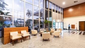 Um hall espaçoso com balcão de recepção, área de estar e grandes janelas com vista para o exterior.
