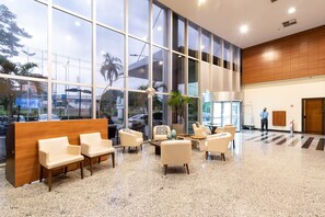 Un vestíbulo amplio con mostrador de recepción, zona de estar y grandes ventanales con vistas al exterior.