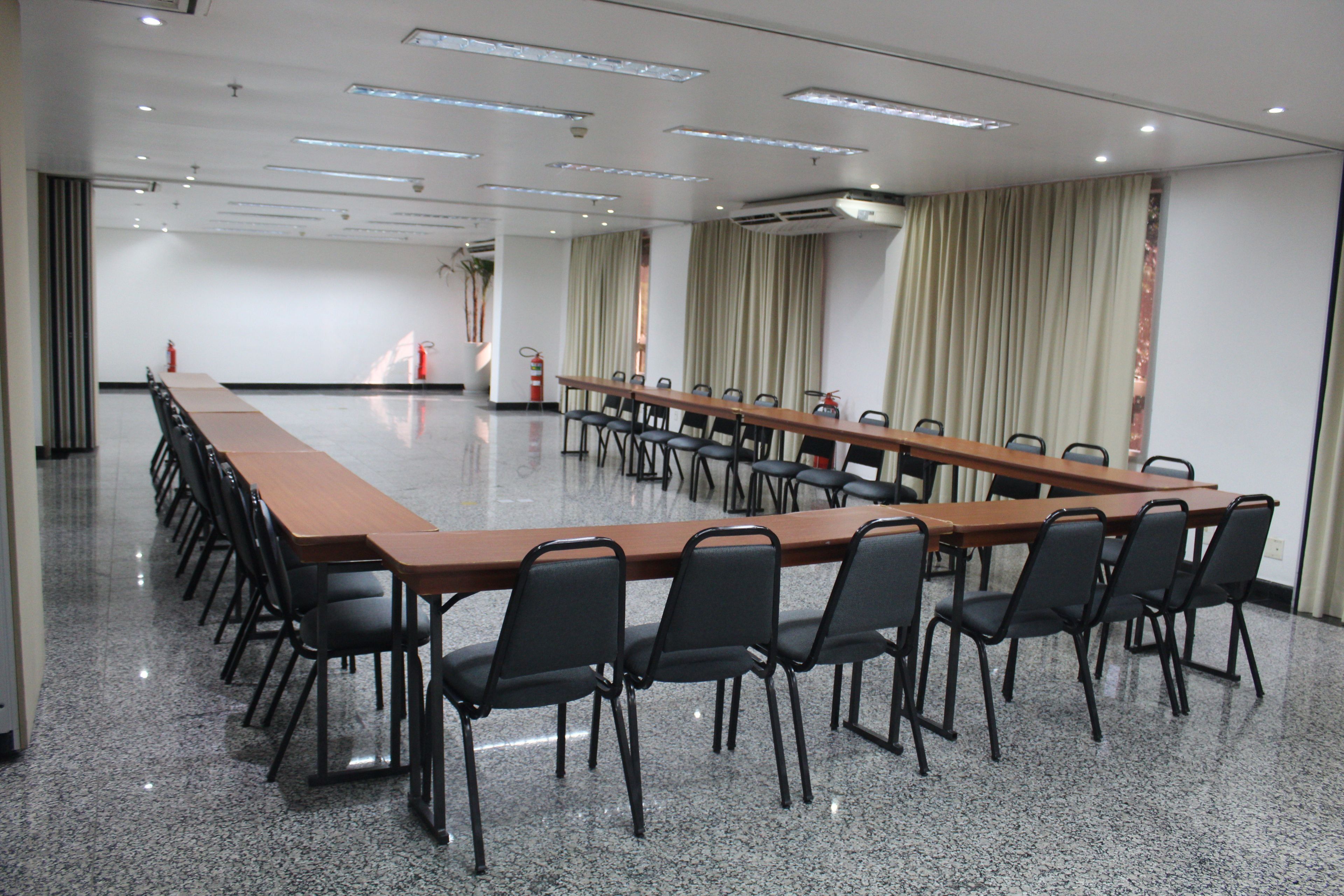 A conference room with a long table and chairs, air conditioning units, and curtains.