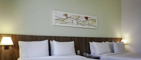 Habitación de hotel con dos camas, cabecero de madera, una obra de arte colgada en la pared y lámparas de noche.