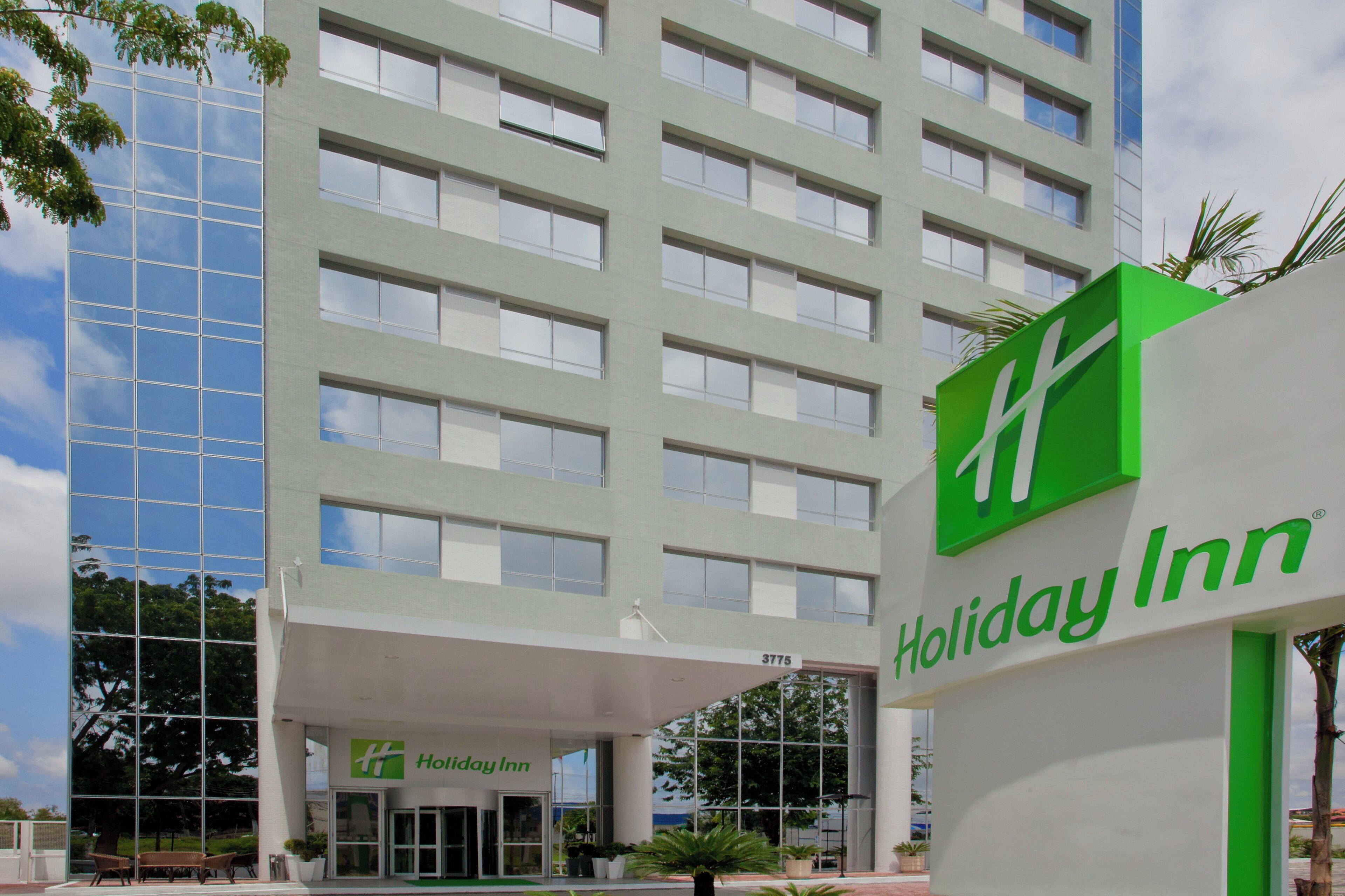Edificio de hotel Holiday Inn con fachada moderna, ventanas amplias y un logotipo verde destacado.