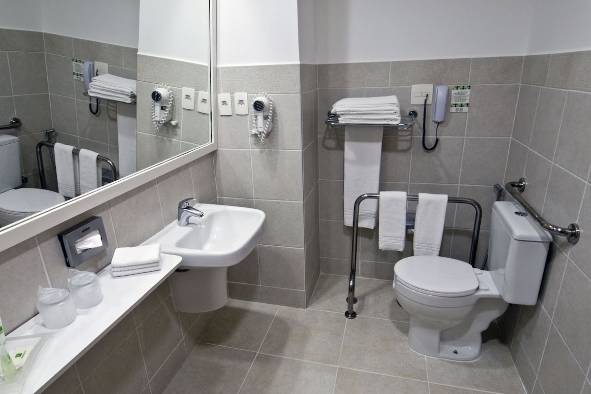 A modern bathroom with a sink, toilet, and hand dryer.