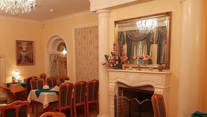 A dining area with multiple tables and chairs, a fireplace, and a large mirror above it. - Hotel Polaris (Swinoujscie)