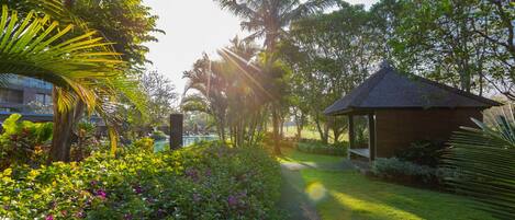 A pathway leading to a gazebo surrounded by lush greenery and palm trees.