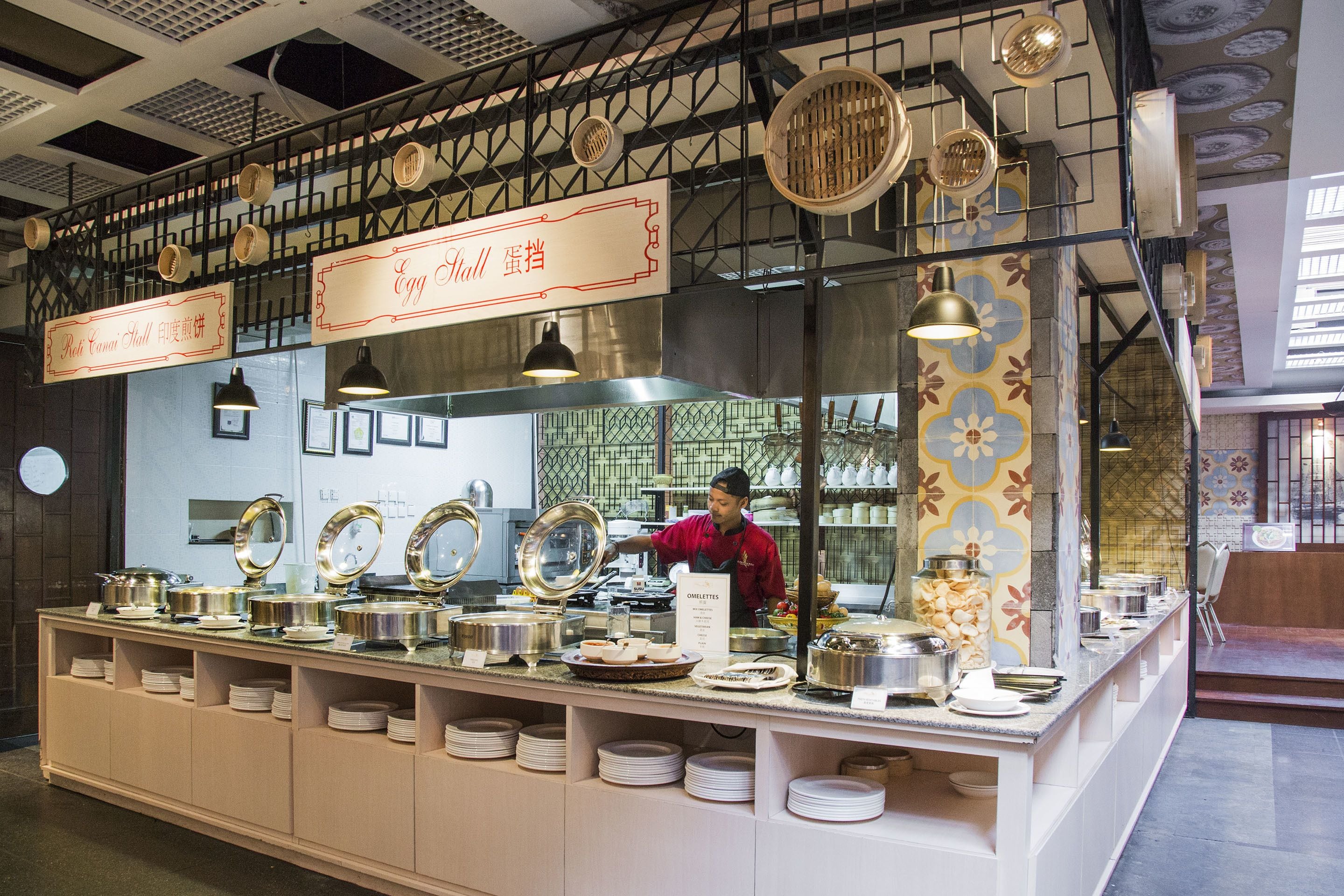 A buffet setup with multiple serving stations, a chef preparing food, and a variety of dishes displayed on the counter.
