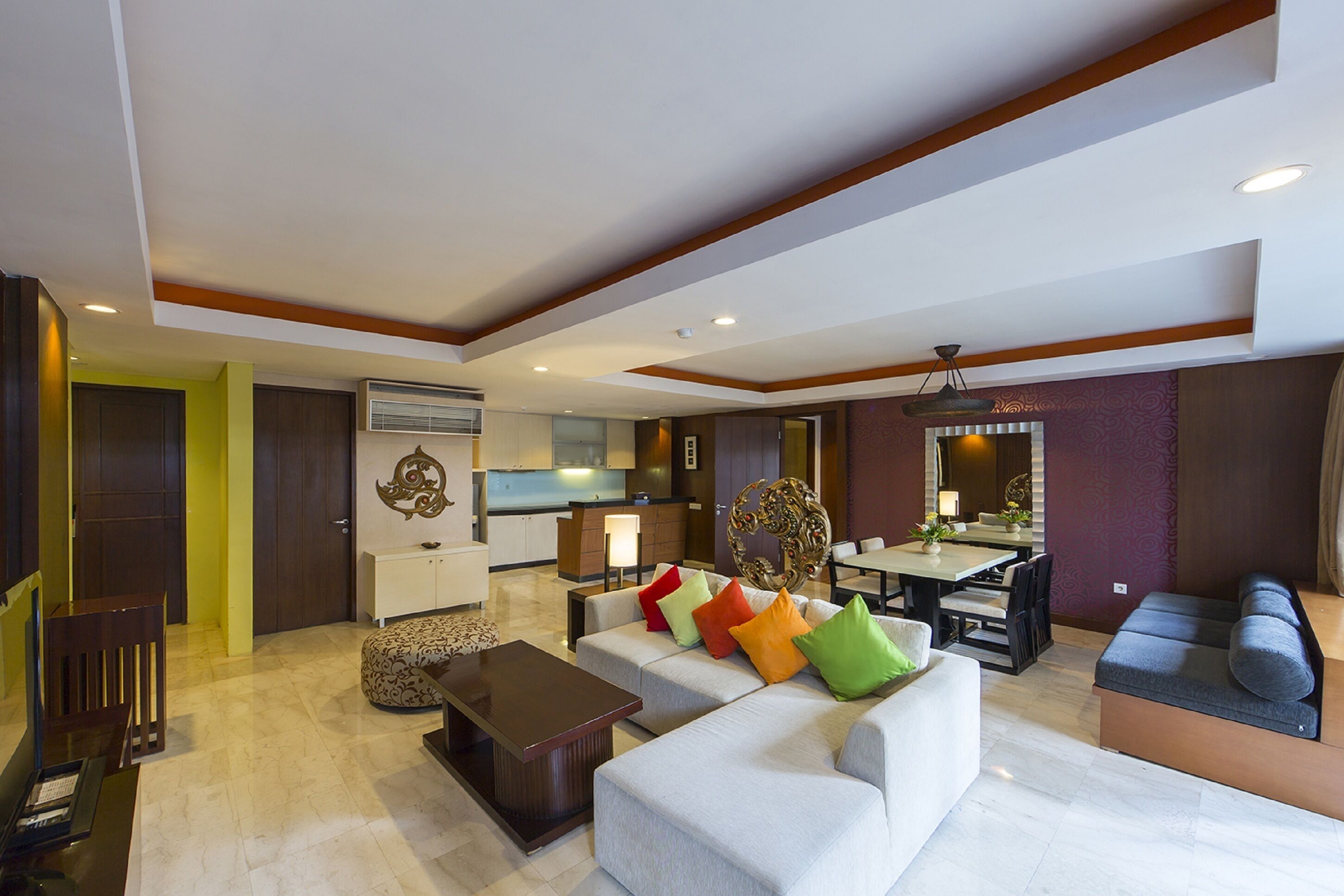 A modern living room with a sofa, coffee table, and a dining area with a table and chairs.