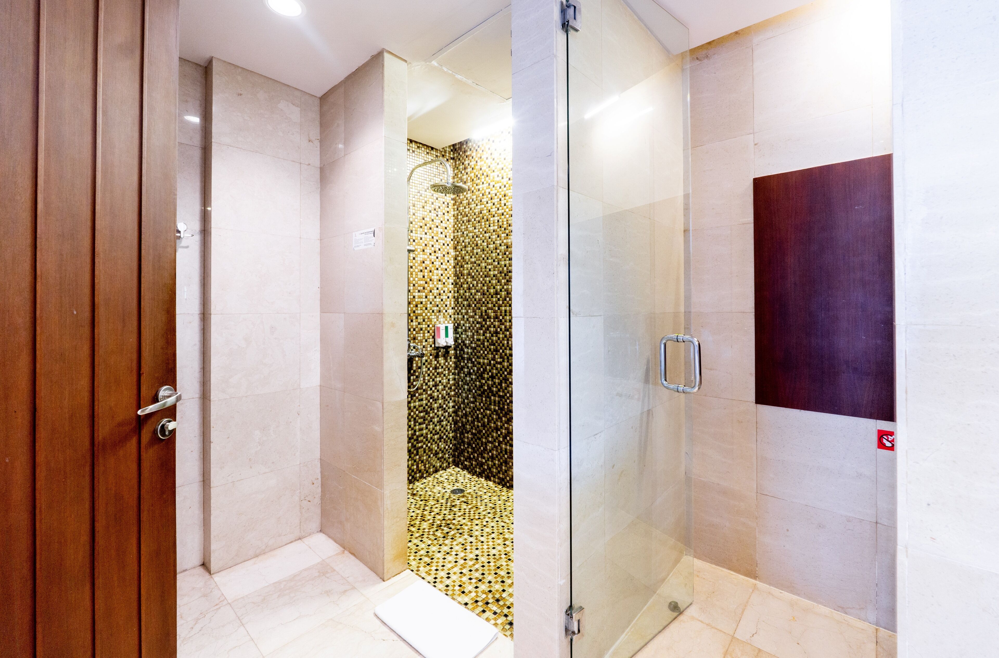 Un bagno moderno con cabina doccia in vetro, porta in legno e pavimento piastrellato.