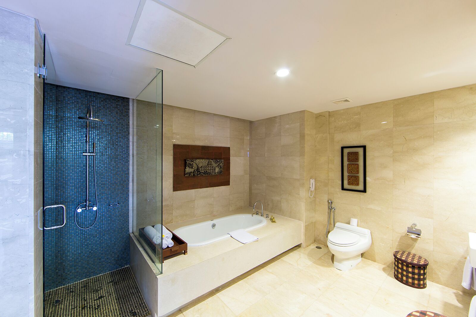 A modern bathroom with a glass-enclosed shower, a freestanding bathtub, a toilet, and a small stool.
