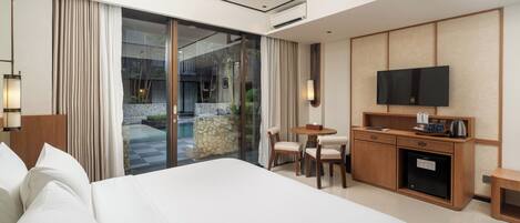 Une chambre d’hôtel avec un grand lit, un bureau avec une télévision, une petite table et une vue sur une piscine et un espace extérieur.
