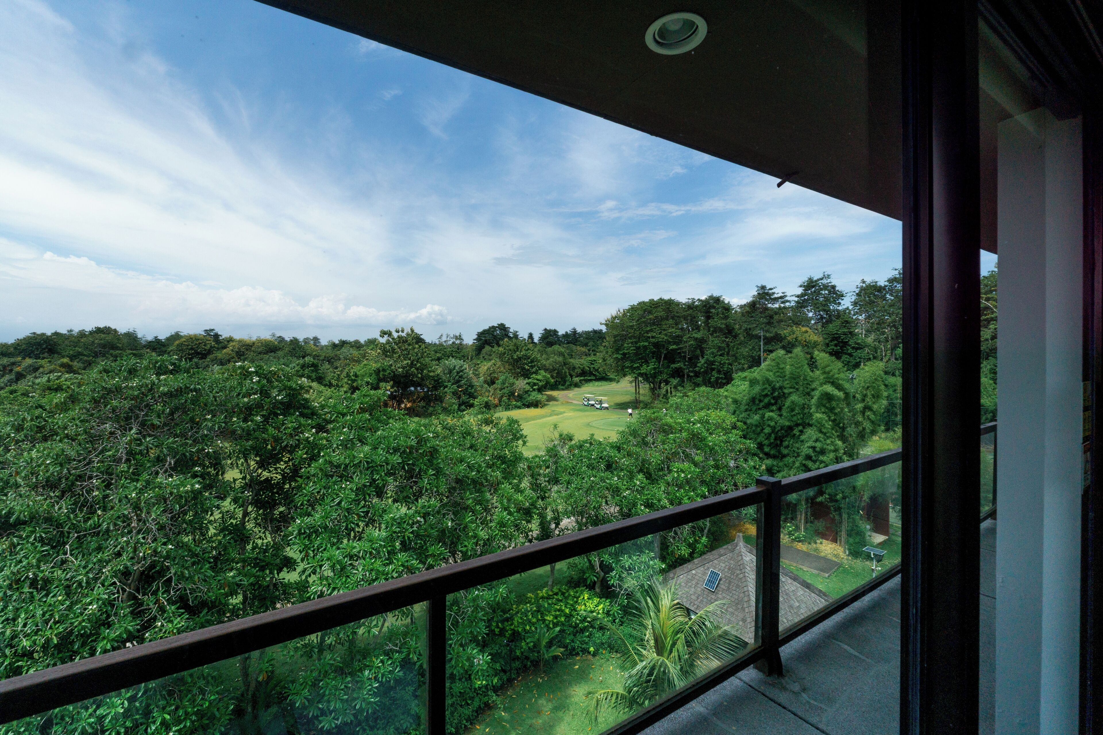 A balcony with a view of a lush green landscape and a golf course.