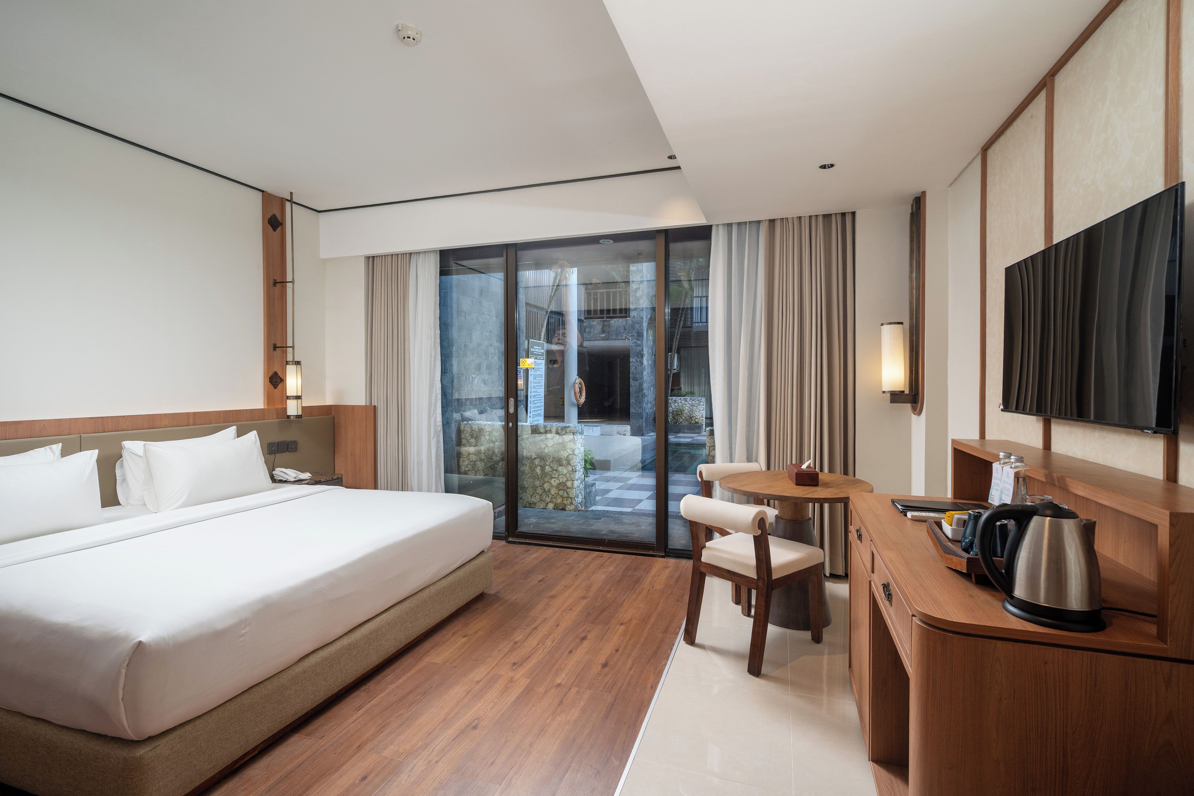 Habitación de hotel con una cama grande, un escritorio con silla, televisor y vistas al exterior.