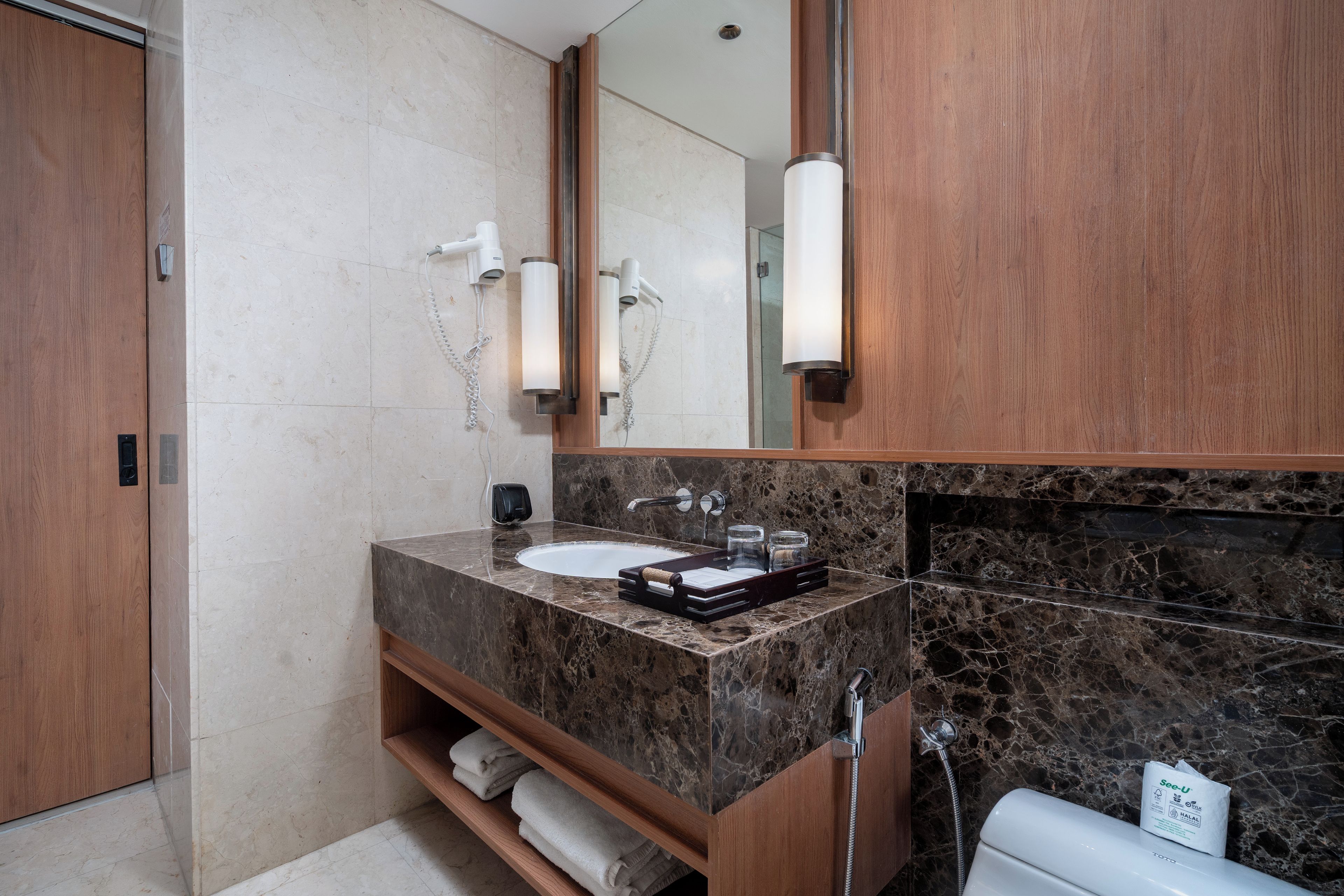 A modern bathroom with a marble sink, wooden vanity, and a large mirror.