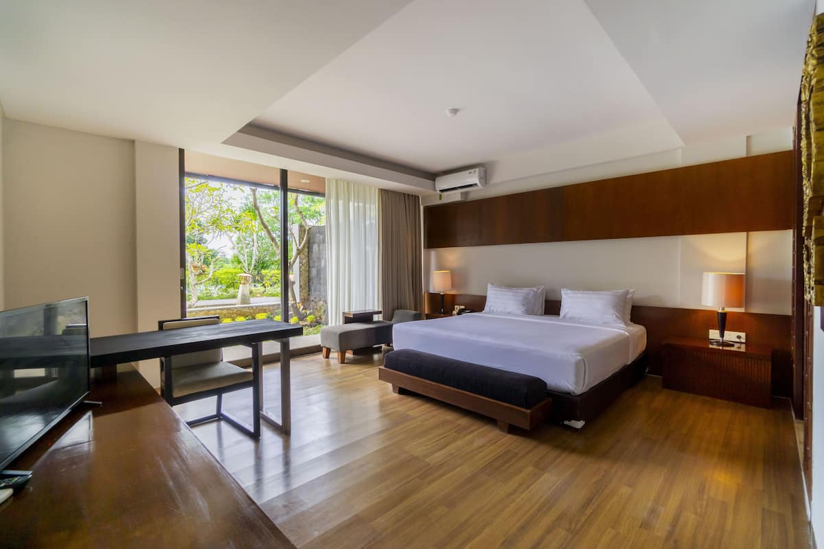 A modern hotel room with a large bed, a desk, and a TV.