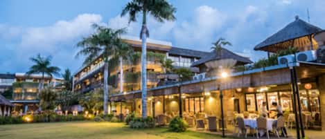 A hotel with multiple dining areas, outdoor seating, and a well-lit courtyard.