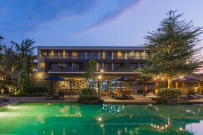 Ein Hotel mit Pool, Außenbereich und einer gut beleuchteten Fassade.