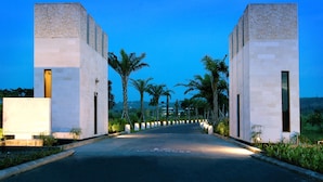 A modern building with a symmetrical facade, a central pathway, and palm trees.