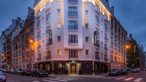 Un hôtel à plusieurs étages, doté d’une entrée imposante, de balcons et d’une façade bien éclairée.