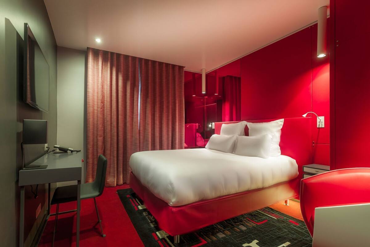 Une chambre d’hôtel moderne équipée d’un lit, d’un bureau, d’une chaise et d’un téléviseur.
