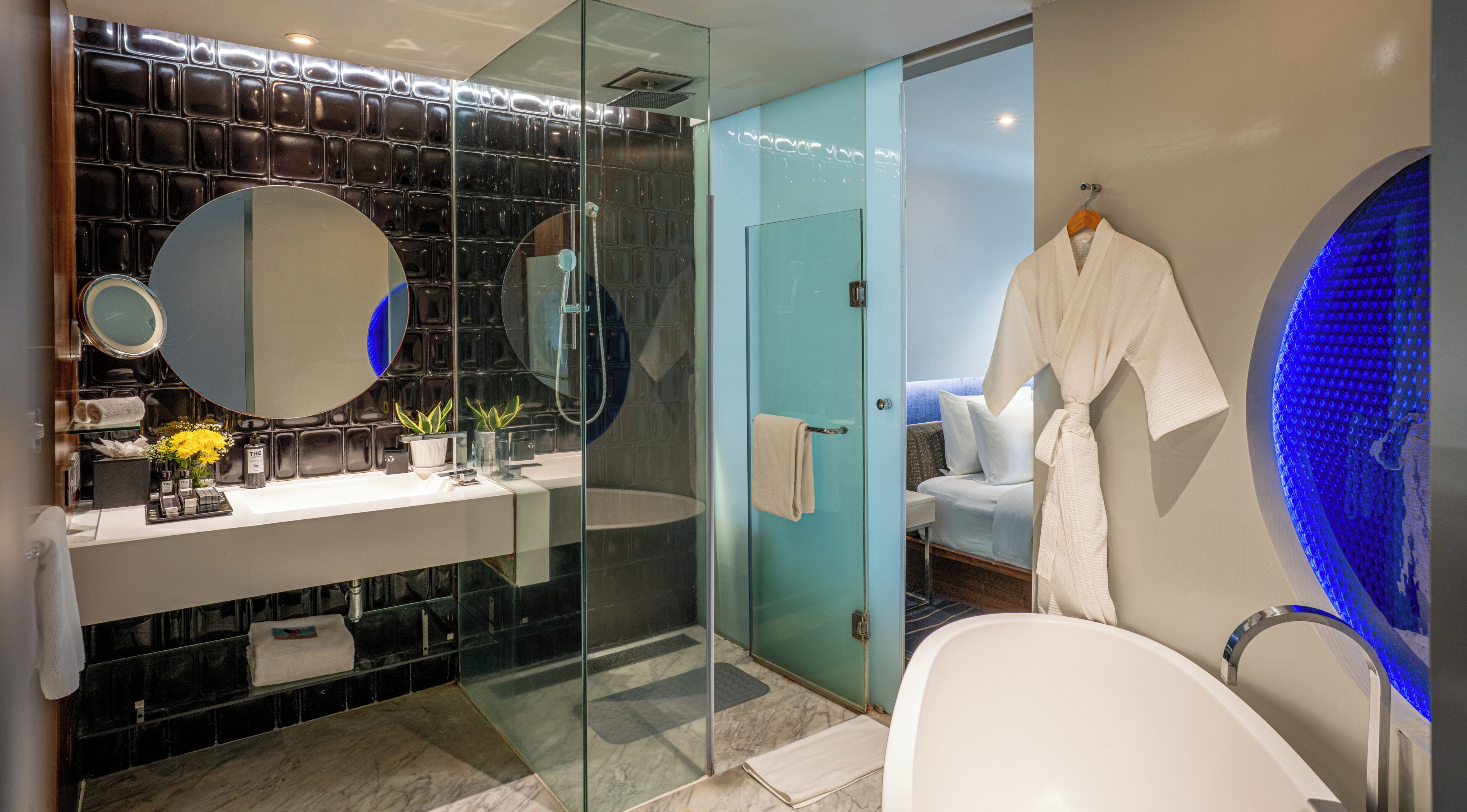 Un baño moderno con cabina de ducha de vidrio, bañera blanca y un espejo grande.