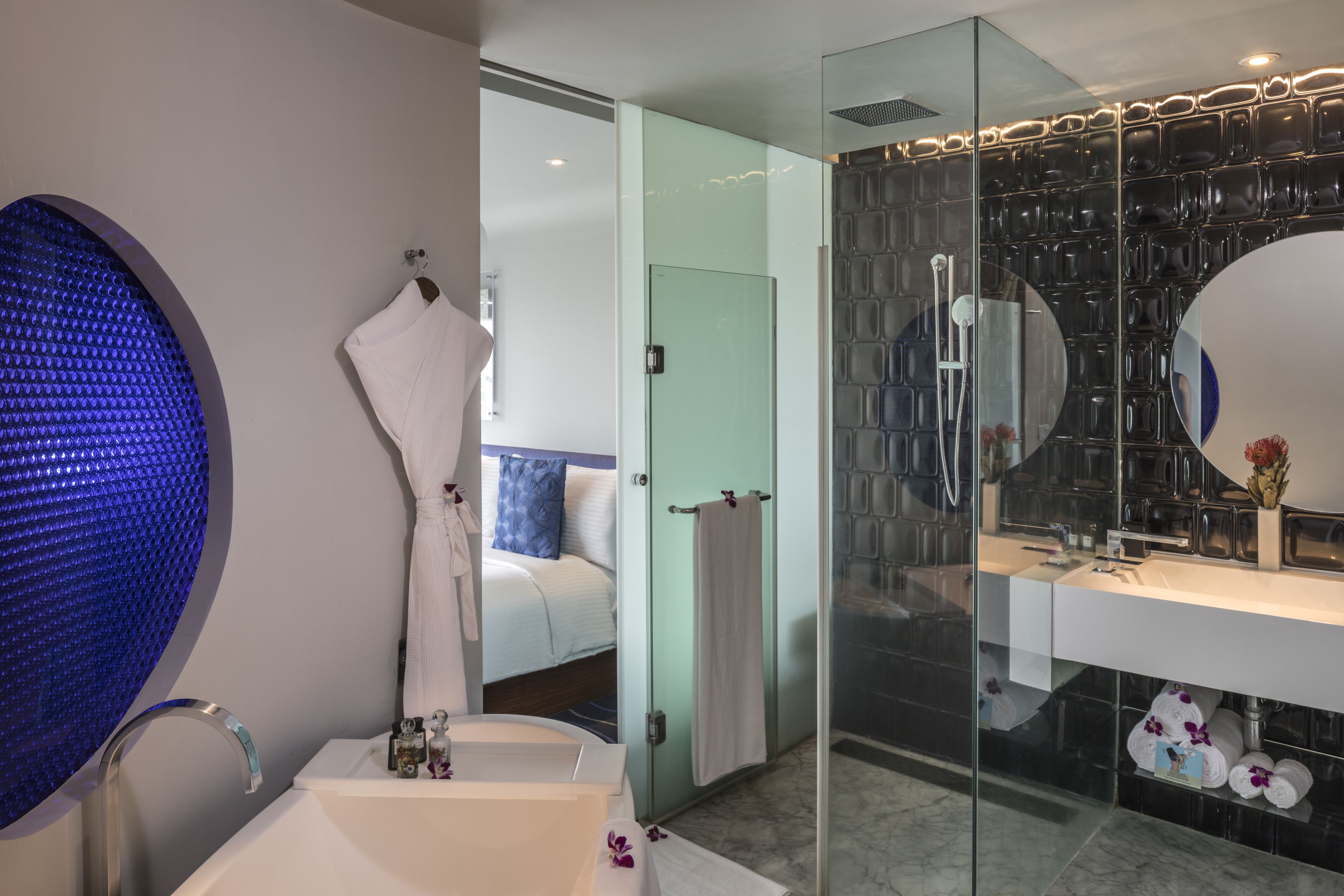 A modern bathroom with a glass shower enclosure, a large mirror, and a white bathtub.