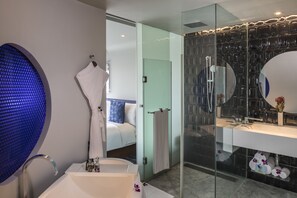 A modern bathroom with a glass shower enclosure, a large mirror, and a white bathtub.