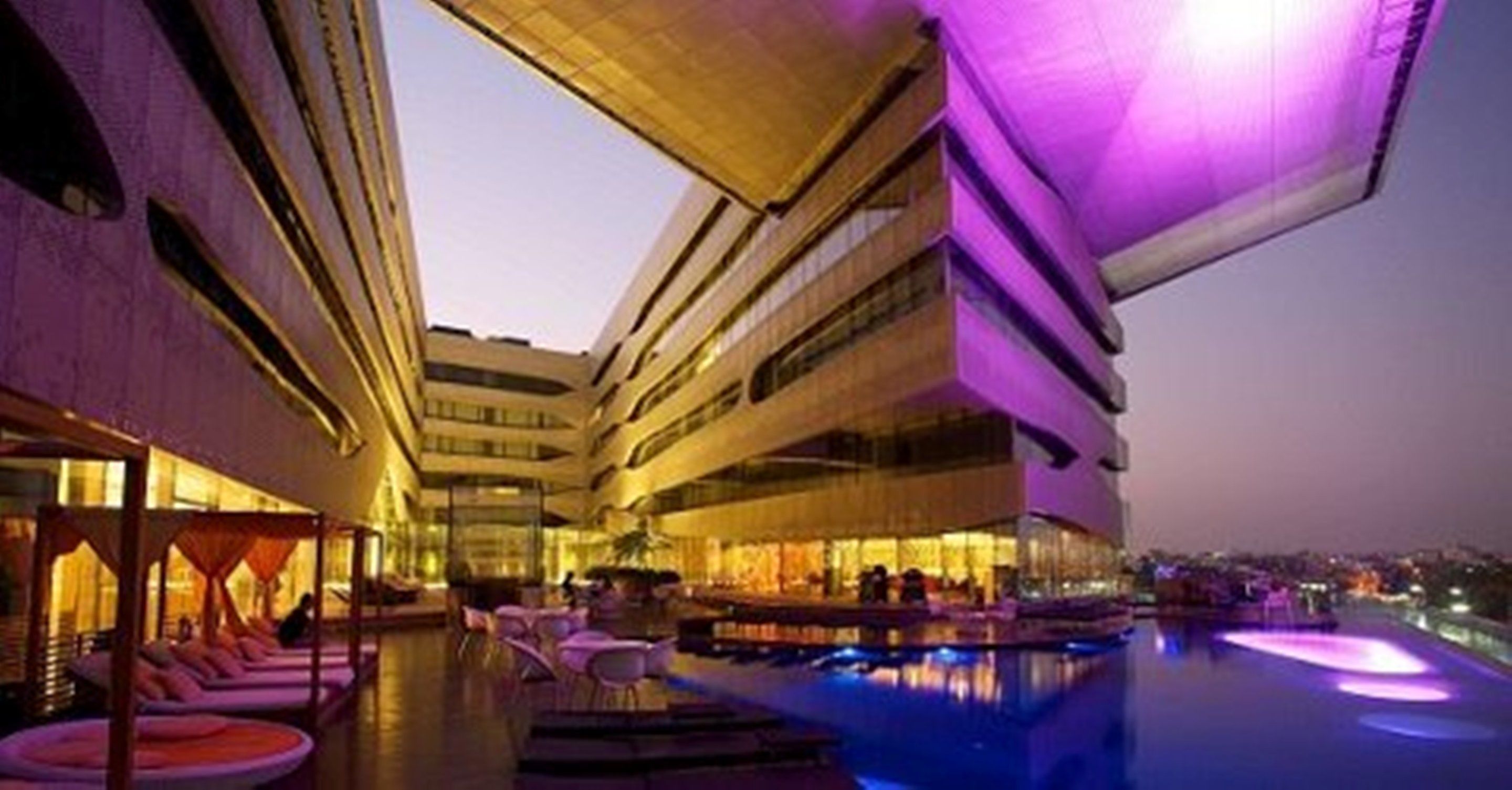 A modern hotel with a pool area, outdoor seating, and a bar.