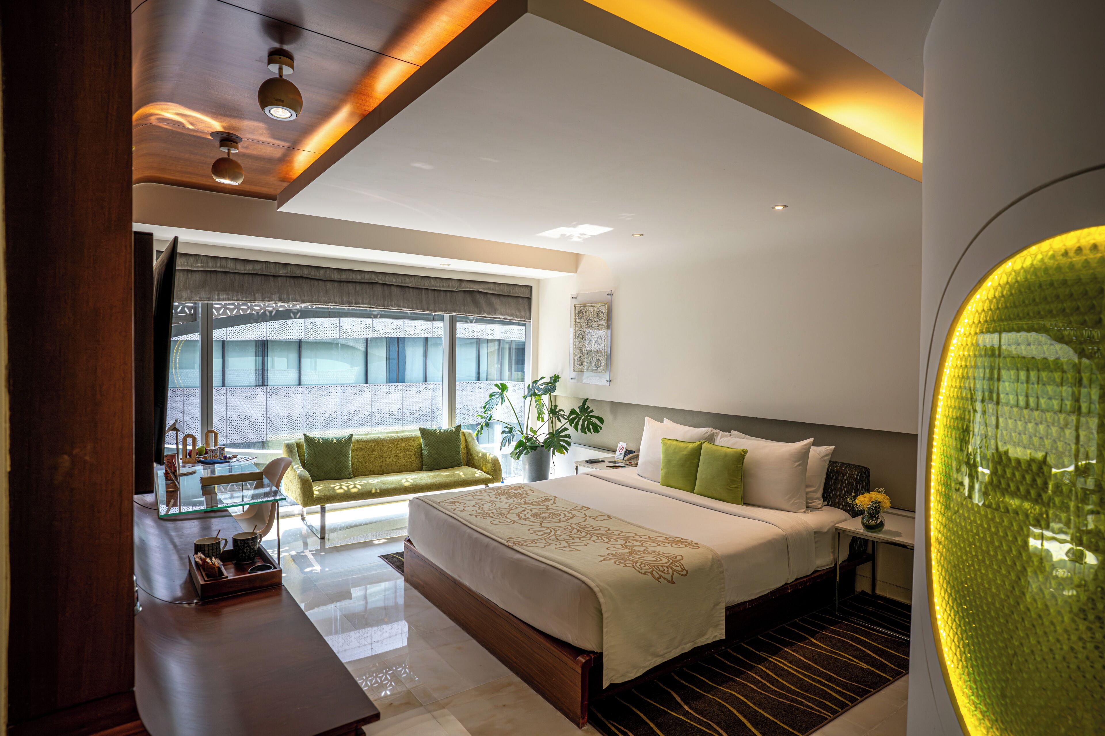 Una habitación de hotel moderna con una cama grande, una zona de estar con sofá y una mesa de comedor.