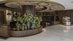 Een receptiehal met een centrale kolom, zithoek en een vitrine.