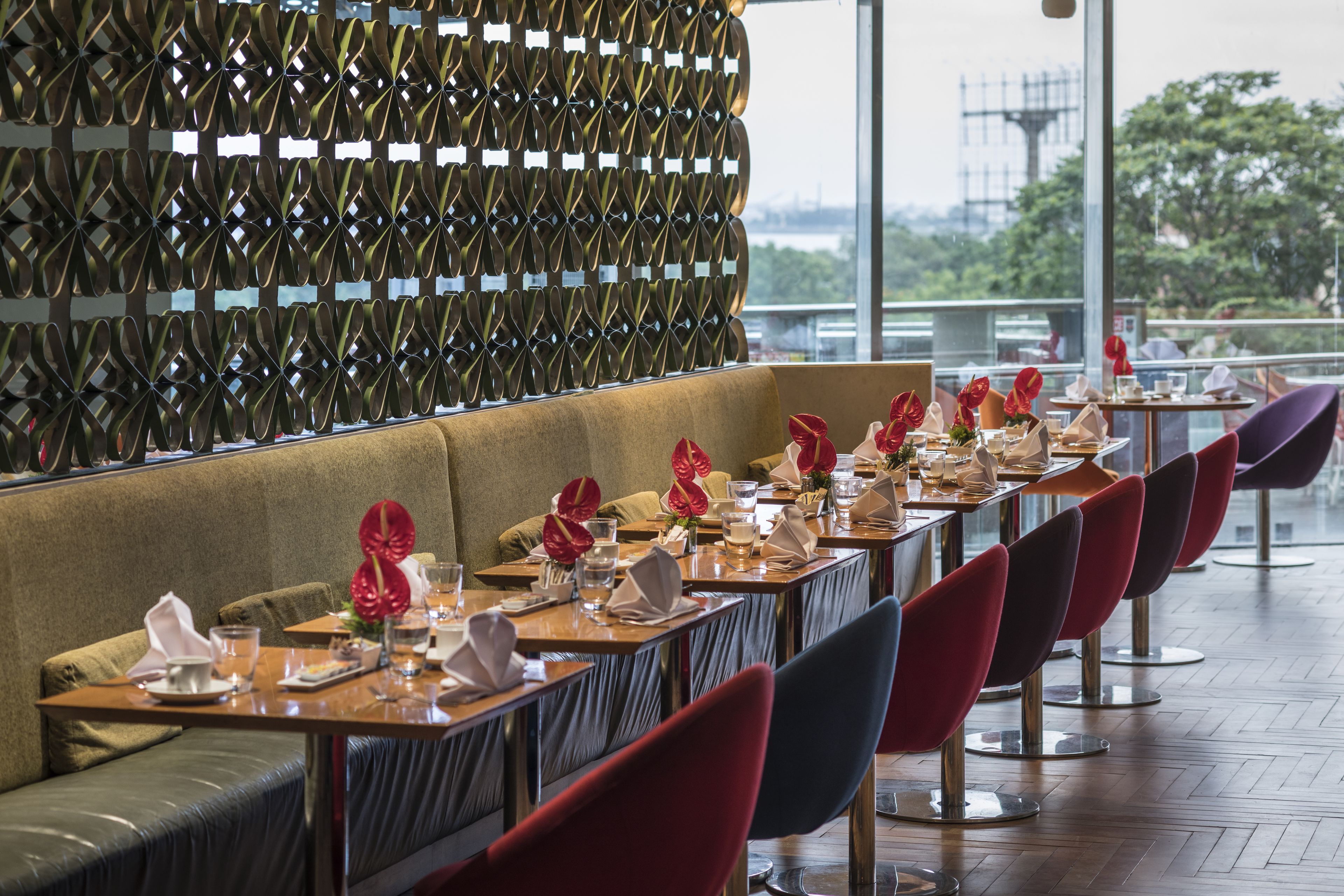 A restaurant with a long table set for dining, a cushioned bench, and a decorative wall.
