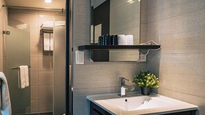 A modern bathroom with a glass shower door, a white sink, a black vanity, and a mirror above the sink. - Hotel Puri Ximen Branch (Taipei)