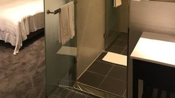 A modern hotel room with a glass-enclosed shower, a bed with white linens, and a small bathroom with a white sink and mirror. - Hotel Puri Ximen Branch (Taipei)