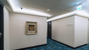 A hallway with a framed artwork on the wall, a blue carpet, and a door with a sign indicating room numbers. - Hotel Puri Ximen Branch (Taipei)