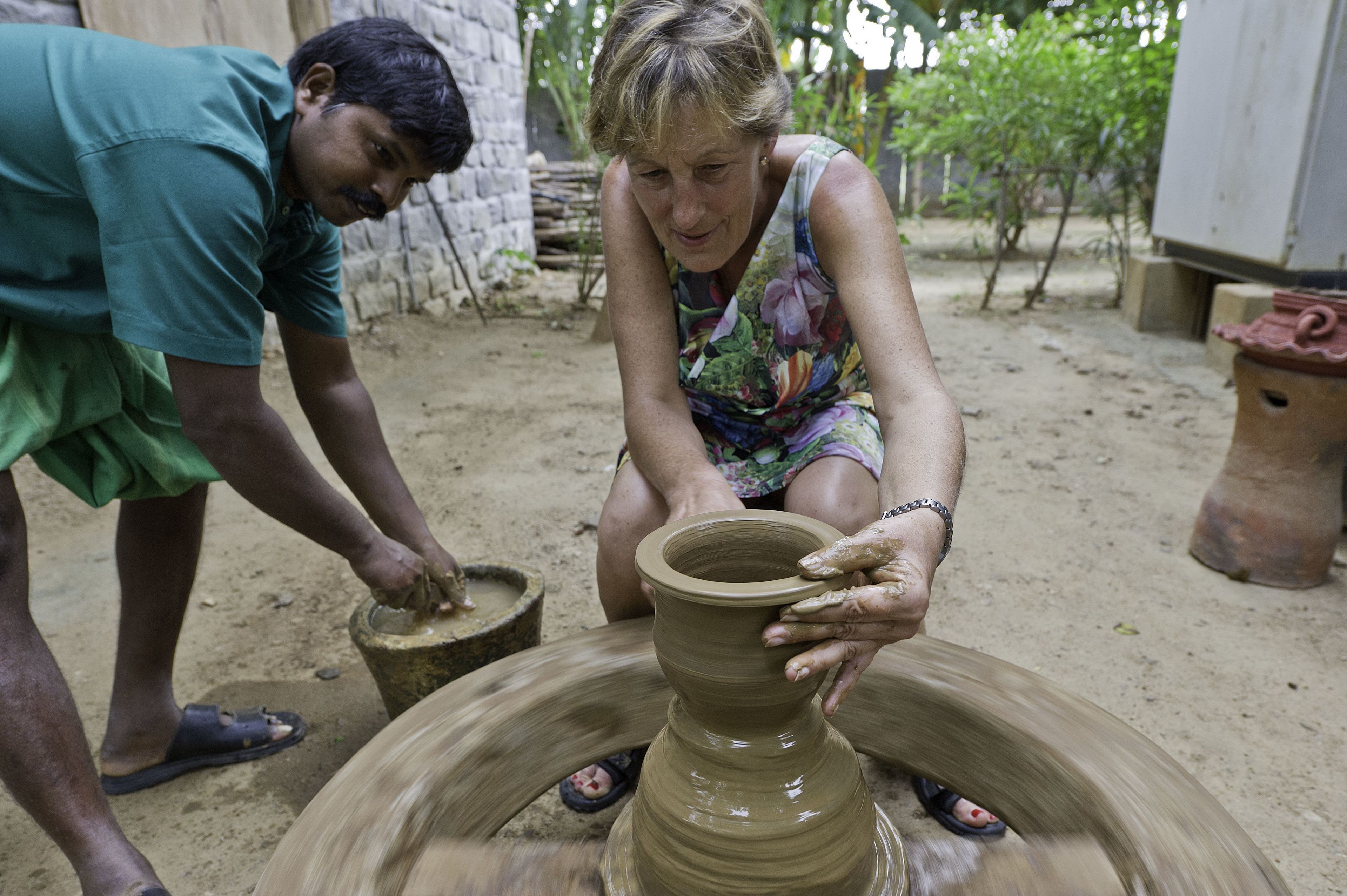 A person shaping a clay pot on a pottery wheel.