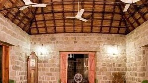 Une pièce aux murs de pierre, au plafond en bois et dotée de deux canapés ornés de coussins à rayures.
