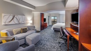 Une chambre d’hôtel moderne équipée d’un canapé, d’un bureau, d’un lit et d’une télévision.