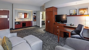 Une chambre d’hôtel équipée d’une kitchenette, d’un téléviseur à écran plat, d’un bureau avec une chaise et d’un canapé.