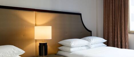 Una habitación de hotel con cama, una mesita de noche con lámpara y una ventana con cortinas.
