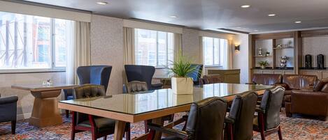 A conference room with a glass table, leather chairs, a potted plant, and a view of the city through large windows.