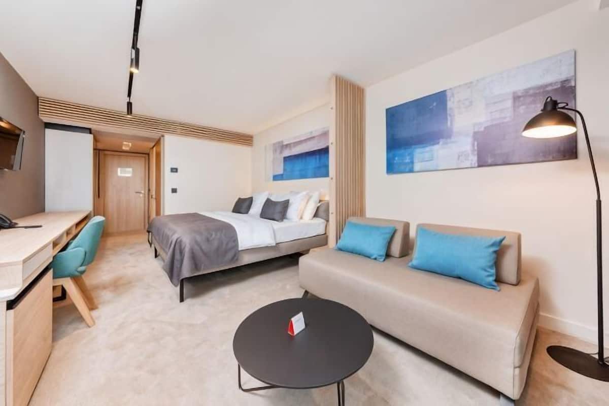 Una habitación de hotel con cama, sofá, escritorio y una silla.