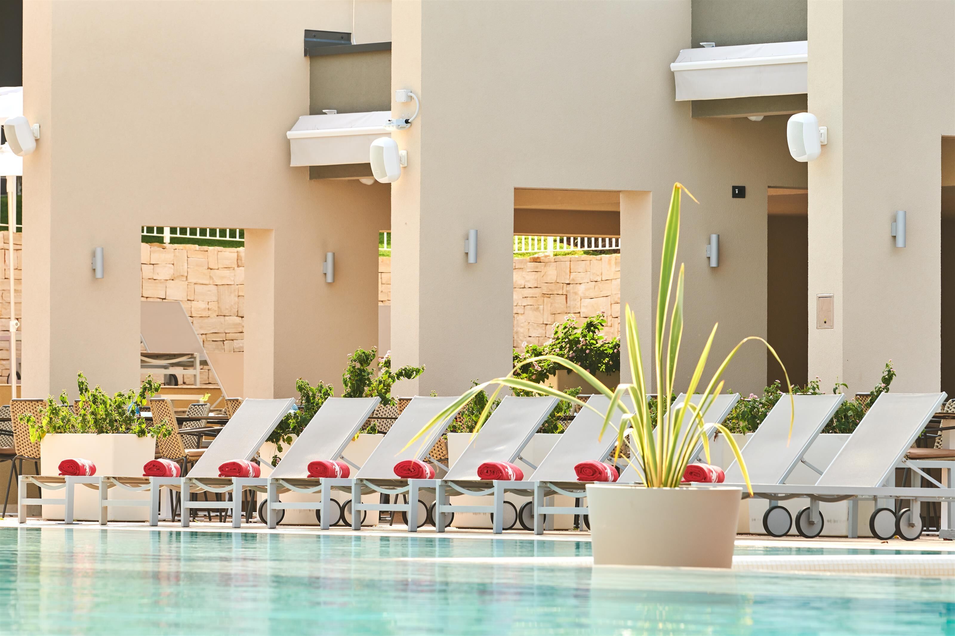 A poolside area with lounge chairs and potted plants.