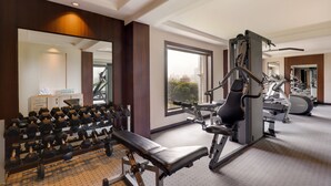 Une salle de sport équipée de machines d’exercice, d’un banc et d’haltères.