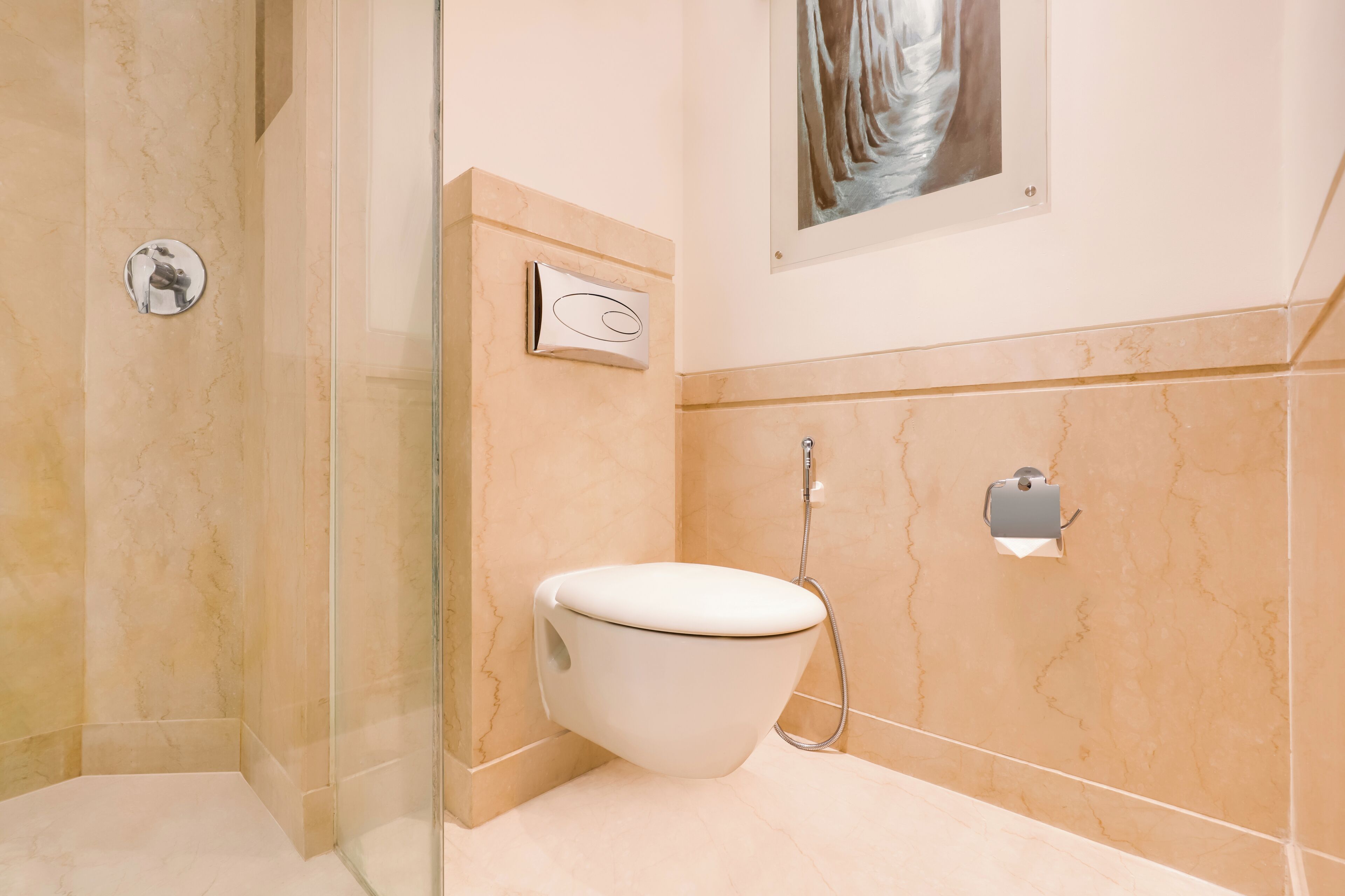 Ein modernes Badezimmer mit einer gläsernen Dusche, einer Toilette und einer Marmorwand.