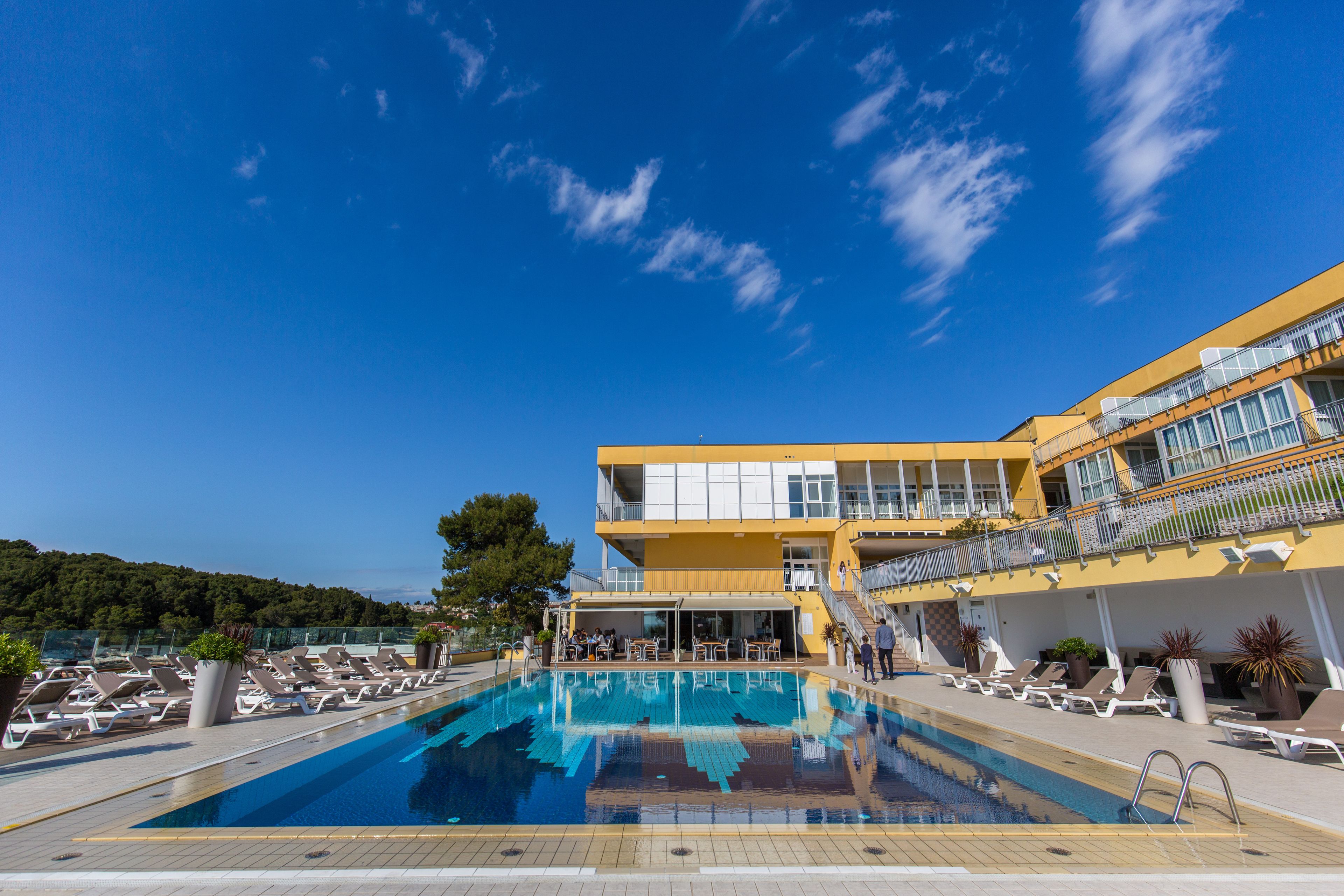 A swimming pool with lounge chairs and a building with balconies.