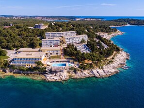 An aerial view of a coastal hotel with multiple buildings, a swimming pool, and a rocky shoreline. - Splendid Golden Rocks Resort (Pula)