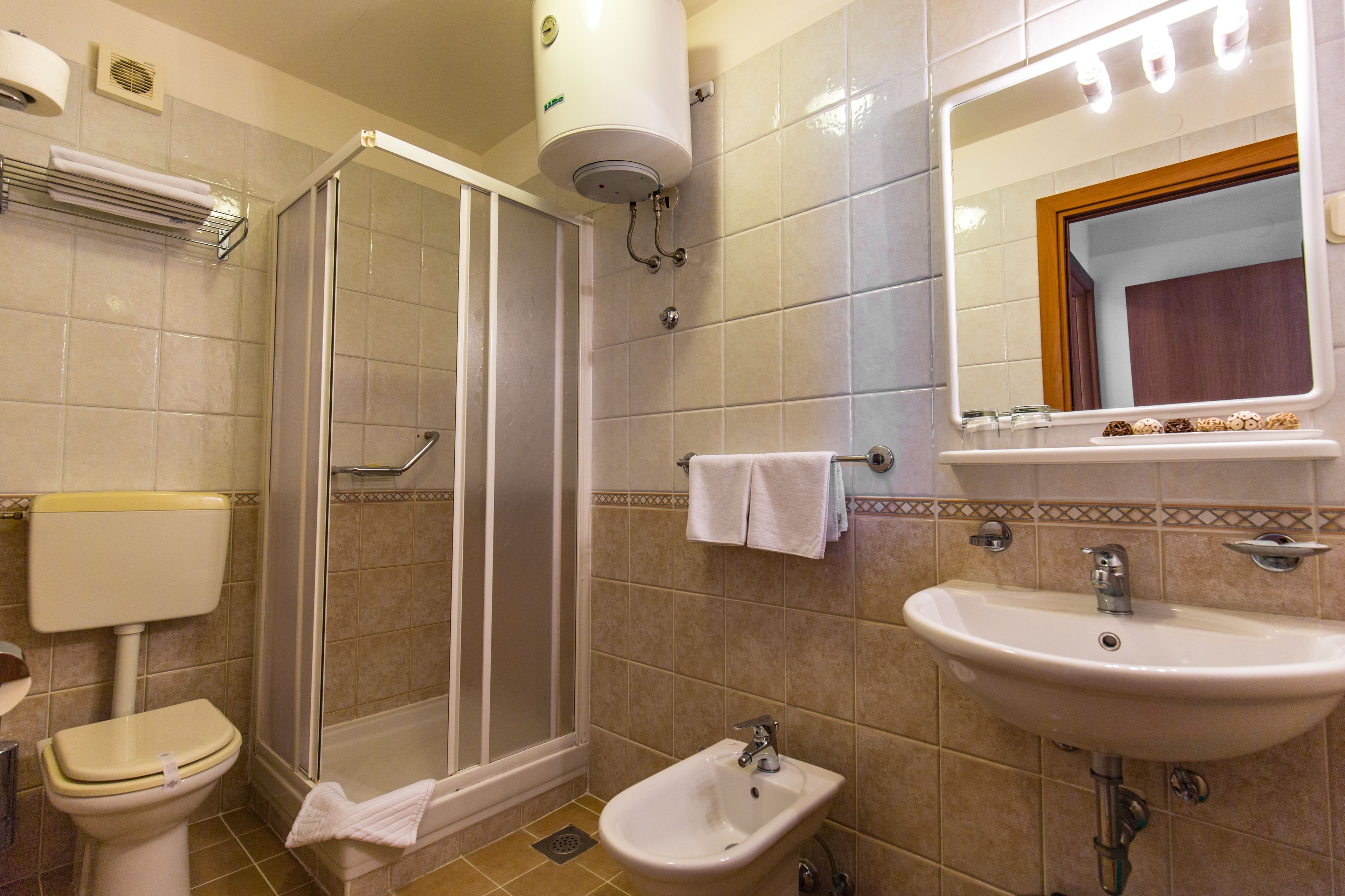 Un baño con inodoro, bidé, ducha, lavabo y espejo.