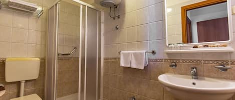 Un baño con inodoro, bidé, ducha, lavabo y espejo.