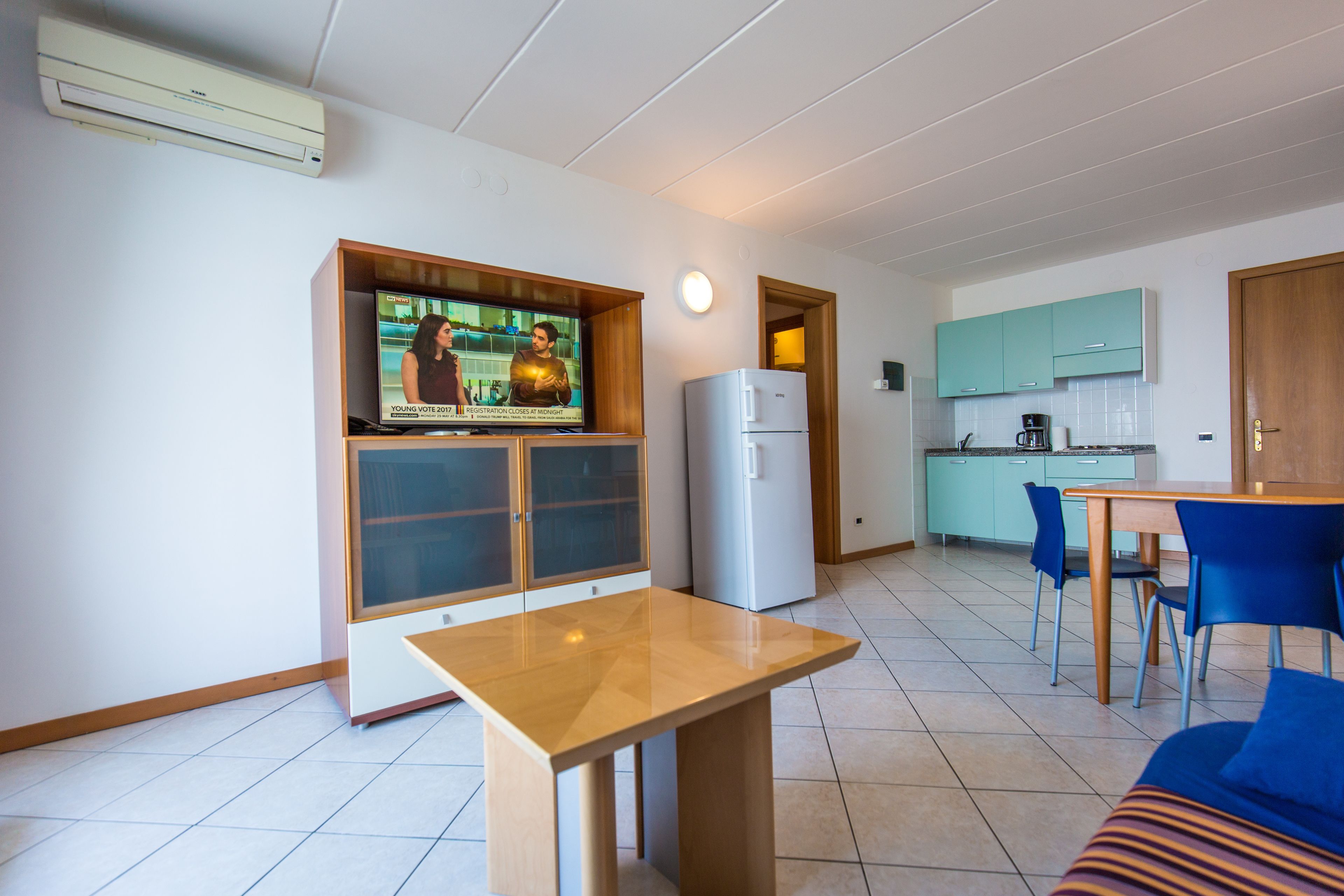 A compact living space with a kitchenette, a dining area, and a TV mounted on a cabinet.